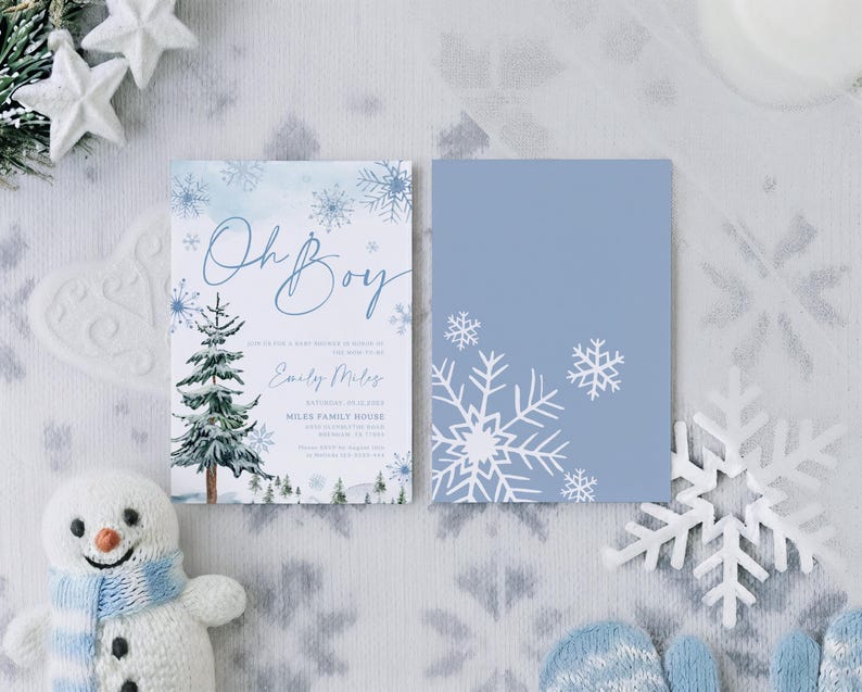 May include: Two rectangular invitation cards featuring a winter theme. The left card displays the text Oh Boy, a watercolor pine tree, and blue snowflakes. The right card is solid light blue with white snowflake illustrations on the corners.