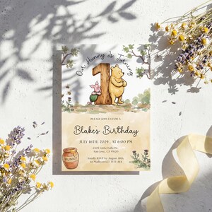 Watercolor illustration of a classic Winnie the Pooh and Piglet standing by a large wooden number one, featuring a honey pot, bees, and thistles on a soft yellow wash background.
