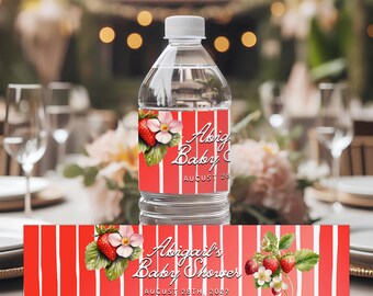 May include: A clear water bottle with a red and white striped label. The label features a strawberry and flower design, with the text "Abigail's Baby Shower" and the date "August 28th, 2027". The bottle is on a table.