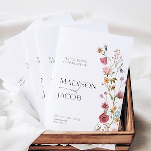 May include: Wedding ceremony program with floral design. The program is white with black text and features a floral border with pink, red, and yellow flowers. The text reads "The Wedding Ceremony of Madison and Jacob, August 24th, 2024, Avaita Garden, Houston, TX."
