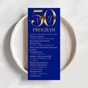 以下が含まれることがあります： 金色の文字で「50」と「PROGRAM」の文字が入った、ネイビーブルーのイベントプログラム。夕食、乾杯、ダンスなど、お祝いのスケジュールが詳細に記載されています。プログラムは明るい木製のプレートに置かれています。