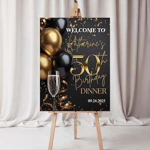 Può includere: Un cartello nero e oro per una cena di compleanno su un cavalletto. Il cartello recita "Benvenuti al 50° compleanno di Katherine" con scritte dorate e include palloncini oro e neri, coriandoli e un calice di champagne. La data è 24/09/2025.