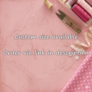 May include: Sewing supplies including metal scissors, a wooden spool, a white measuring tape, and pink polka dot fabric. The text reads: Custom size available. Order via link in description. These items are arranged on a pink marble surface.