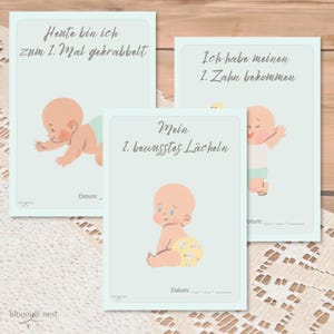 May include: Three blue cards with illustrations of babies and text in German. The text on the cards reads "Heute bin ich zum 1. Mal gekrabbelt", "Ich habe meinen 1. Zahn bekommen", and "Mein 1. bewusstes Lächeln". Each card has a space for a date.