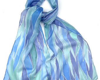 Bufanda de seda pintada a mano con diseño abstracto de olas en azul y aguamarina.