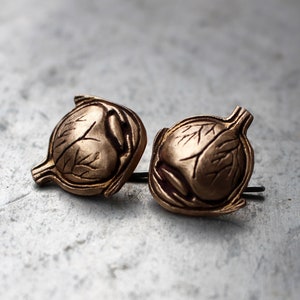 May include: A pair of gold-toned earrings shaped like human eyes. The earrings are detailed with veins and have a realistic look.