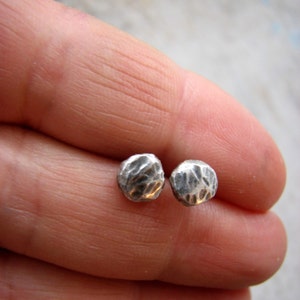 May include: A pair of silver stud earrings with a hammered texture.
