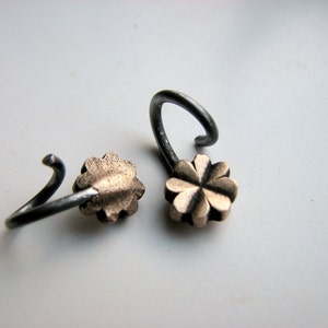 May include: Two silver earrings with a gold four-leaf clover charm.