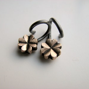 May include: A pair of silver earrings with a four-leaf clover design in gold.