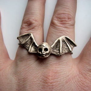Anillo de calavera con alas de murciélago y doble dedo.
