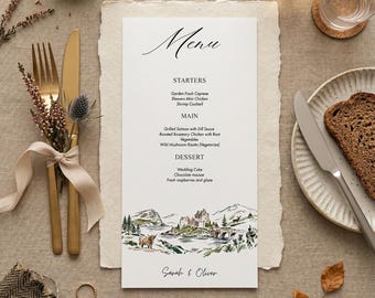 May include: A wedding menu card with a scenic illustration at the bottom, featuring a castle, mountains, and a lake. The menu lists starters, main courses, and dessert options. Gold cutlery and a plate with bread are also visible.