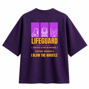 May include: A dark purple short-sleeve t-shirt featuring a graphic on the back with three white icons above the text LIFEGUARD, DRAMA PREVENTION SERVICE, CERTIFIED SITUATION WATCHER, EVERYONE OVERREACTS, and I BLOW THE WHISTLE in orange and white.