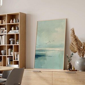 May include: A framed vertical wall art print featuring an abstract landscape in shades of pale green, teal, and white. The composition depicts a calm horizon line with a small flock of black birds flying across the center of the sky.