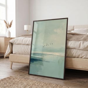 May include: A rectangular framed wall art piece featuring an abstract landscape painting in soft shades of sage green, pale blue, and white. The artwork depicts a calm horizon line with a small flock of black birds flying across the center.