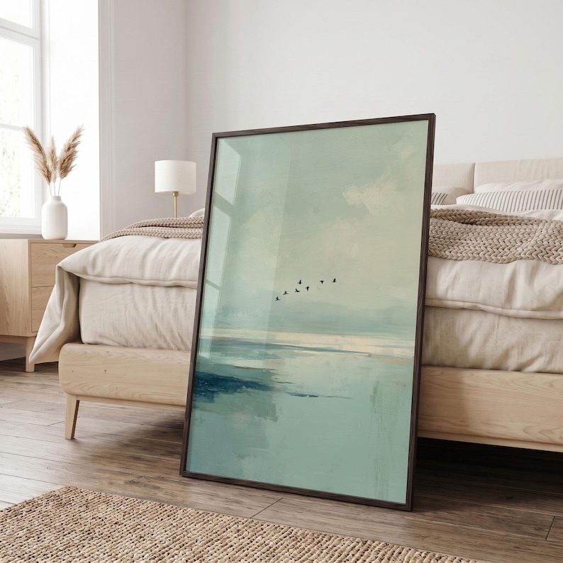 May include: A rectangular framed wall art piece featuring an abstract landscape painting in soft shades of sage green, pale blue, and white. The artwork depicts a calm horizon line with a small flock of black birds flying across the center.