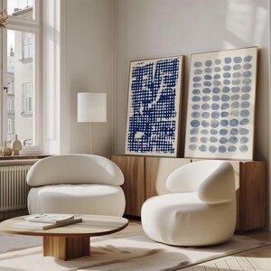 May include: Two framed rectangular wall art prints featuring abstract patterns. One print displays a dense grid of dark blue dots, while the other shows a structured pattern of light blue circular shapes. Both are displayed on a wooden sideboard.