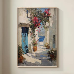 May include: Oil painting of a sunlit alleyway with white buildings, a blue door, and vibrant red flowers. The artwork features a coastal scene with a view of the sea. The painting is framed in a light-colored wooden frame.