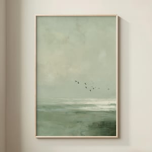 May include: A framed abstract landscape painting in shades of green and white. The artwork depicts a seascape with a flock of birds in flight against a muted sky. The painting has a textured, brushstroke appearance, creating a serene and natural aesthetic.