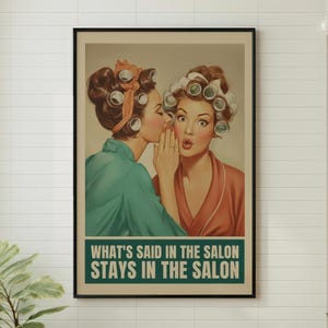 May include: Framed vintage-style print featuring two women in curlers, one whispering to the other. The woman being whispered to has a surprised expression. The print has the text "WHAT'S SAID IN THE SALON STAYS IN THE SALON".