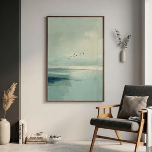 May include: A vertical rectangular wall art print featuring an abstract landscape in shades of sage green, pale blue, and dark navy. The composition depicts a calm horizon line with a small flock of black birds flying across the cloudy sky.