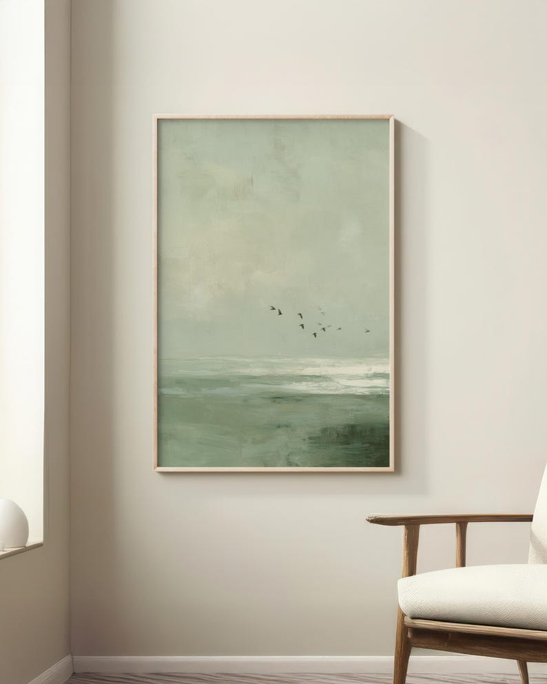 May include: A framed landscape painting in muted greens and off-white tones. The artwork shows a seascape with a flock of birds in flight. The wooden frame complements the artwork's natural aesthetic, suitable for home decor.