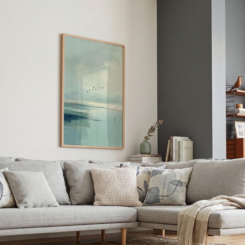 May include: A rectangular wall art print in a light wood frame featuring an abstract landscape painting with soft blue and green tones, depicting a calm horizon line and a small flock of birds flying across a hazy, muted sky.