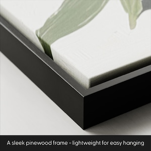 May include: Close-up of a black pinewood frame. The frame surrounds a canvas with a green and white abstract design. The text at the bottom reads: "A sleek pinewood frame - lightweight for easy hanging."