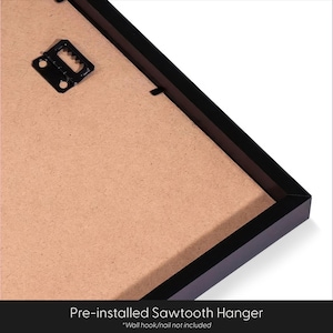 May include: Close-up of the back of a framed artwork. The frame is black, and the backing is a light brown color. A pre-installed sawtooth hanger is visible, ready for wall mounting. The text at the bottom reads "Pre-installed Sawtooth Hanger".