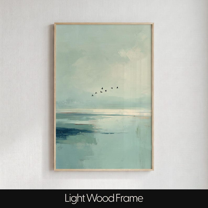 May include: A vertical wall art print in a light wood frame featuring an abstract landscape painting. The artwork displays soft shades of pale blue, teal, and white, depicting a calm body of water under a cloudy sky with a small flock of birds.