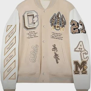 May include: A beige and white baseball jacket with embroidered patches. The patches include the letters "ACM", the number "23", and the words "AC Milan" and "Urgil Ablah".