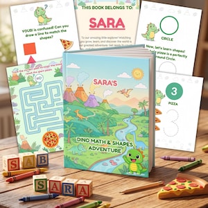 Peut inclure: Un livre pour enfants à couverture rigide personnalisé intitulé SARA'S DINO MATH & SHAPES ADVENTURE, illustré d'un paysage préhistorique coloré avec des volcans et des dinosaures. Le livre est entouré de blocs alphabet en bois épelant SARA et de crayons.