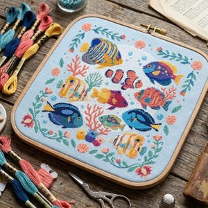 May include: A cross-stitch embroidery featuring colorful fish in an underwater scene. The design includes various fish species, coral, and floral elements, all framed within a wooden hoop. Embroidery floss in various colors is arranged around the hoop.
