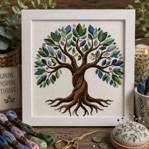 Può includere: Un ricamo a punto croce incorniciato raffigurante un albero con un tronco marrone spesso e intrecciato e radici esposte. La chioma è composta da numerose piccole foglie ricamate nei toni del verde, blu e viola, con piccoli fiori rosa.