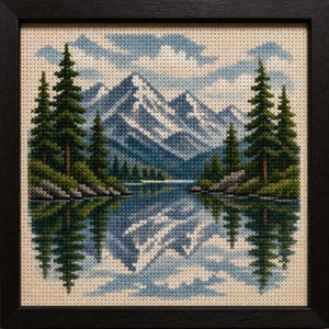 Puede incluir: Arte de paisaje en punto de cruz enmarcado en negro. La escena representa una cordillera reflejada en un lago, con árboles de hoja perenne en las orillas. El cielo es azul con nubes blancas. La obra de arte es detallada y colorida.