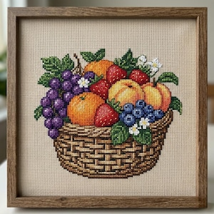 May include: Cross-stitch picture of a basket filled with fruit. The basket includes oranges, peaches, strawberries, blueberries, and grapes, with green leaves and small white flowers. The artwork is framed in a wooden frame.
