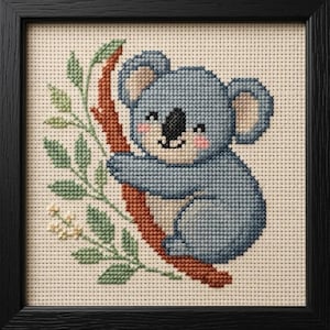 Peut inclure: Broderie au point de croix d'un koala sur une branche d'arbre, encadrée en noir. Le koala est bleu clair avec des joues roses et un nez noir. La branche est marron et les feuilles sont vertes. Le fond est en tissu crème.