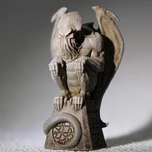May include: A detailed, gray statue of a winged creature with a tentacled face, seated on a pedestal. The statue has a serpent-like tail and intricate carvings. The wings are spread, and the figure is in a crouching position.
