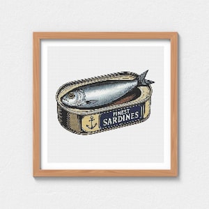Op de afbeelding: Een ingelijste print van een vintage sardineblik. Het blik is open en toont een zilveren vis. Het etiket luidt "FINEST SARDINES" met een ankersymbool. Het kunstwerk is in kruissteekstijl.
