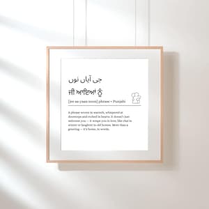 May include: A framed print with Punjabi text and its English translation. The print features the phrase "jee aa-yaan noon" on a white background. The frame is a light wood colour.