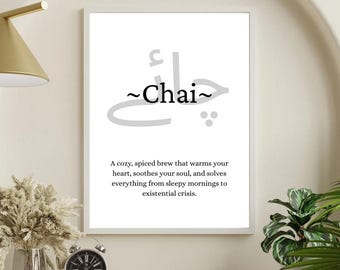 May include: A framed print with the word "Chai" in stylized text. Below the word is a description of Chai as a cozy, spiced brew. The print is displayed on a wall, with a lamp and decorative items in the foreground.