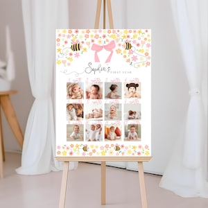 May include: A framed poster on an easel, featuring a collage of baby photos. The poster has a floral and bee design with the text "Sophia's First Year." Each photo is labeled with a month. The easel is made of wood.