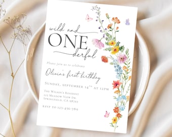 May include: A white invitation card with the text "wild and ONE derful" and "Olivia's first birthday." The card is decorated with colorful watercolor flowers and butterflies. The invitation is on a white plate.