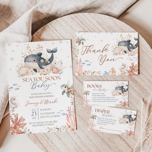 K&ouml;nnte beinhalten: Ein Babyparty-Einladungsset mit Meeresthema. Die Einladung und die dazugeh&ouml;rigen Karten zeigen Illustrationen von Walen, Muscheln und Korallen in sanften Blau-, Beige- und Korallt&ouml;nen. Auf der Einladung steht "Sea You Soon Baby".