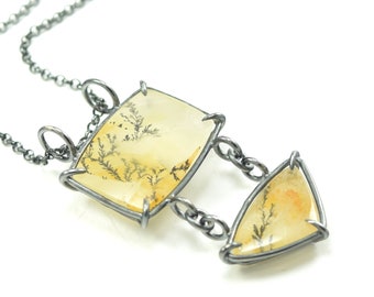 May include: A silver chain necklace with a pendant featuring two yellow and white agate stones set in silver wire.