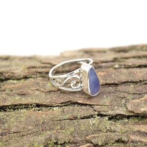 May include: A silver ring with a teardrop-shaped purple gemstone set in a delicate, swirling design.