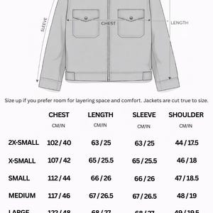 May include: A diagram of a jacket with measurements in inches and centimeters. The text reads "Custom sizing is available" and includes measurements for chest, length, sleeve, and shoulder. Sizes range from 2X-Small to 3X-Large.