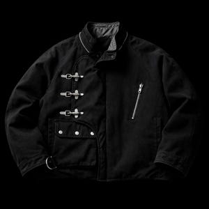 Puede incluir: Chaqueta negra con cierres metálicos plateados y un bolsillo con cremallera. La chaqueta tiene cuello redondo y un pequeño bolsillo con botones plateados. Tiene cierre de cremallera plateado y un anillo plateado en la parte inferior izquierda.