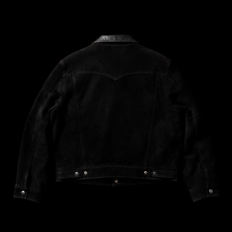 May include: Black denim jacket with a leather collar, viewed from the back. The jacket features silver buttons and a classic design. The dark wash denim gives it a vintage look. A stylish piece for any wardrobe.