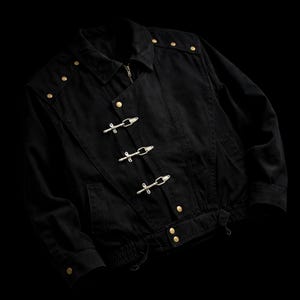 May include: A black jacket featuring a fold-down collar, long sleeves with buttoned cuffs, and a front closure with three silver-toned metal toggle clasps. The garment includes gold-toned metal buttons on the shoulders and waist hem.