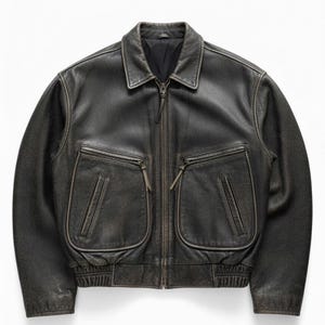 Könnte beinhalten: Dunkelbraune Lederjacke mit Reißverschluss, zwei großen Vordertaschen und einem Kragen. Die Jacke hat ein leicht abgenutztes Aussehen mit sichtbarer Textur und subtilen Farbvariationen. Die Bündchen und der Bund sind gerippt.